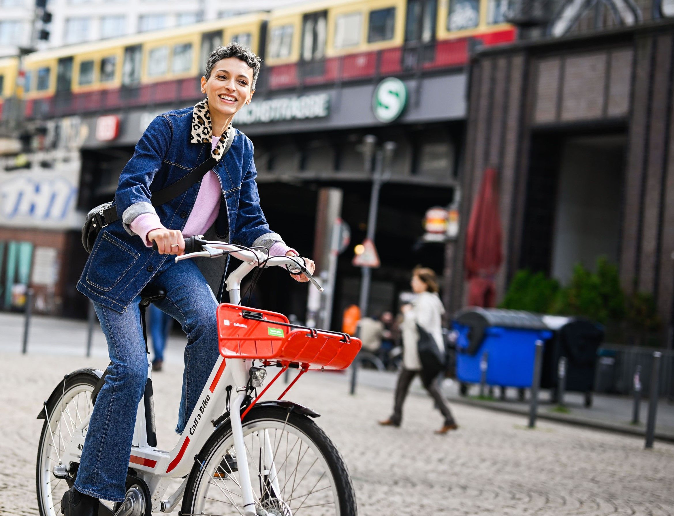 A woman rides past an S-Bahn station in Berlin on Call a Bike.