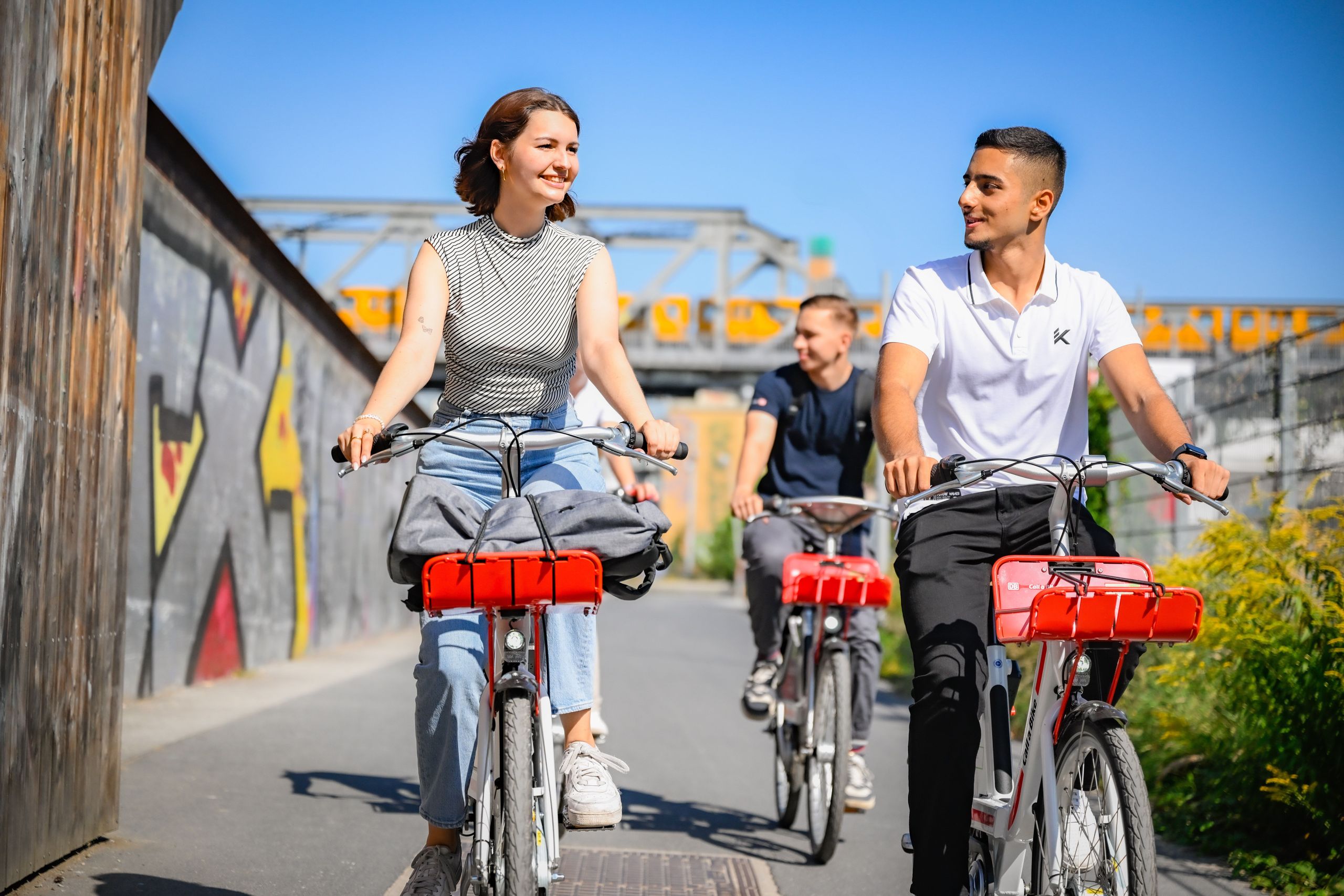 Frau und Mann fahren mit Call a Bike Fahrrädern durch einen Park