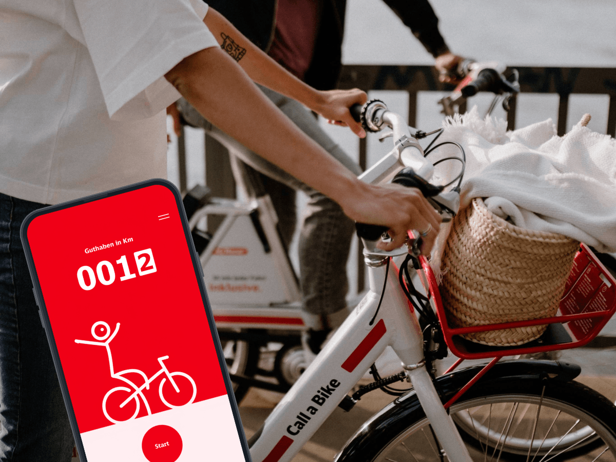 Zwei Personen stehen mit Rädern von Call a Bike auf einer Brücke in Köln. Links ist ein Handy mit Blick in die Rad+ App eingeblendet.