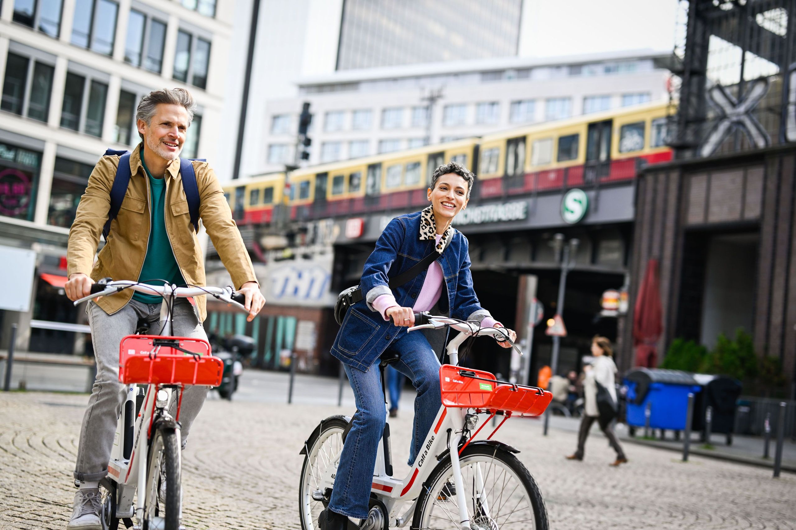 Two people ride past an S-Bahn station in Berlin on two bikes