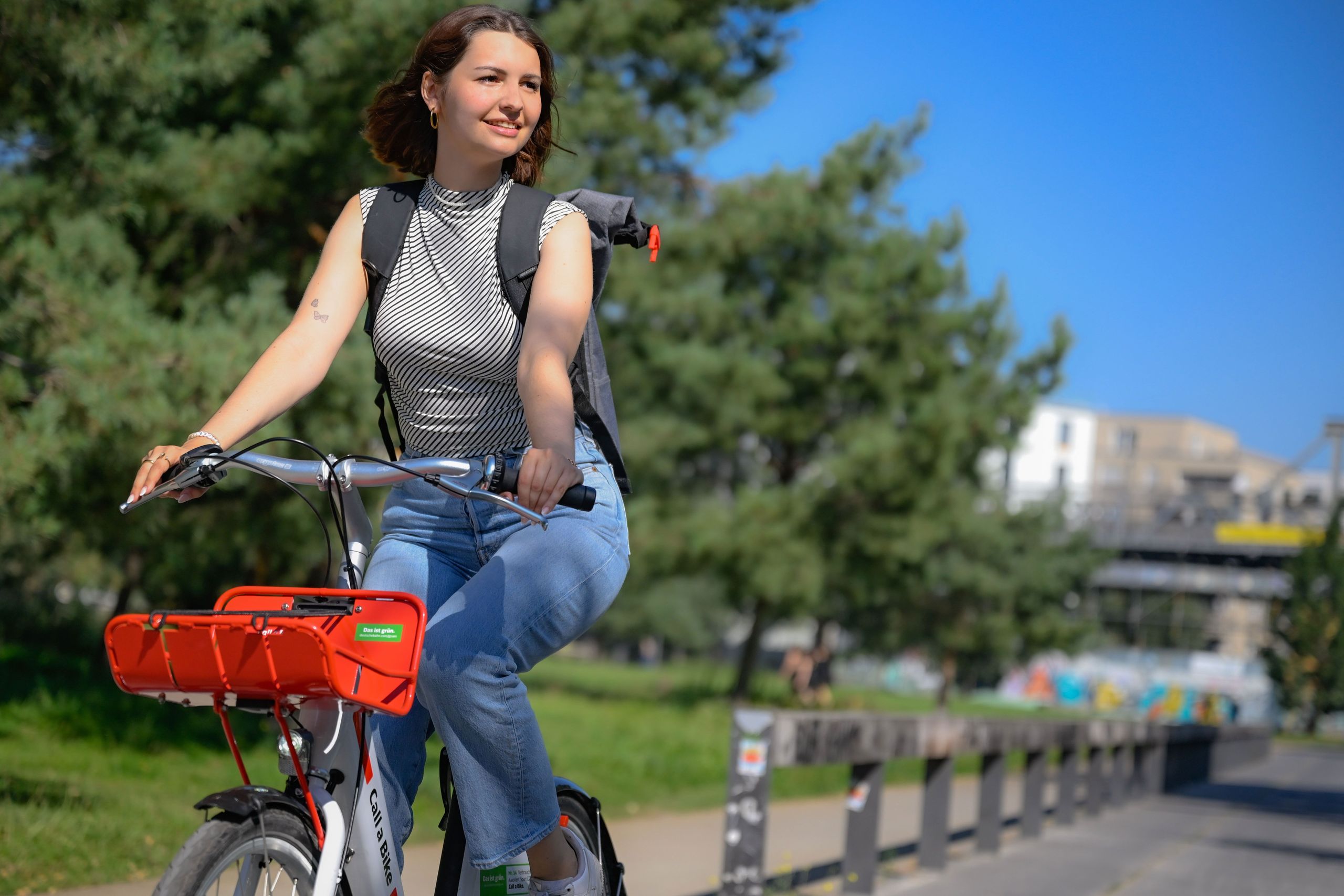 A woman rides a Call a Bike bicycles through a park.